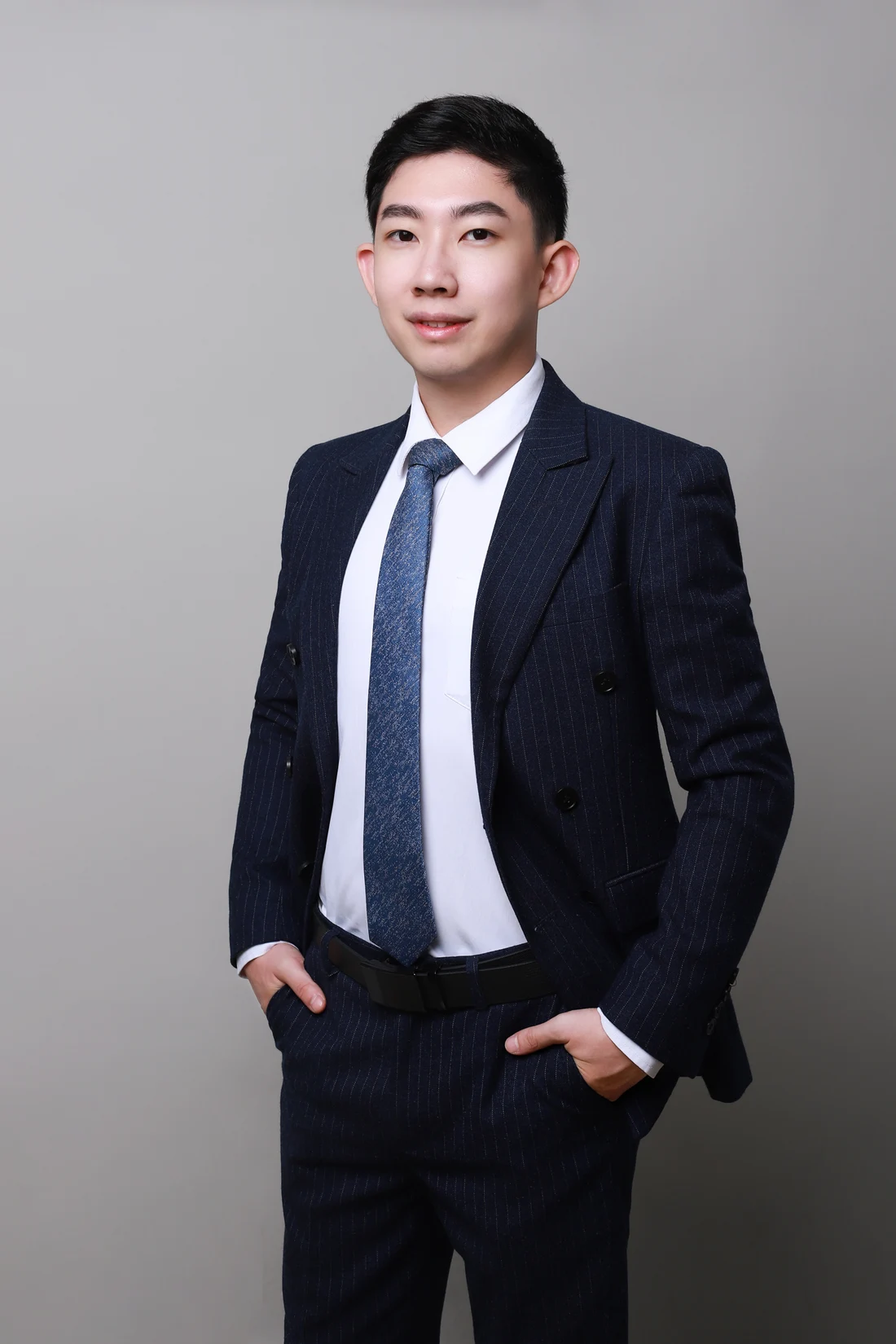 Portrait of Xiao Huang wearing a navy suit.